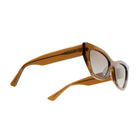 A pair of cat-eye sunglasses with translucent amber brown frames and gradient brown lenses, shown from a three-quarters angle on a solid white background.